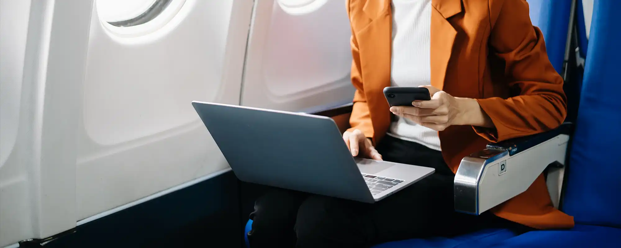Femme utilisant ordinateur et smartphone en avion